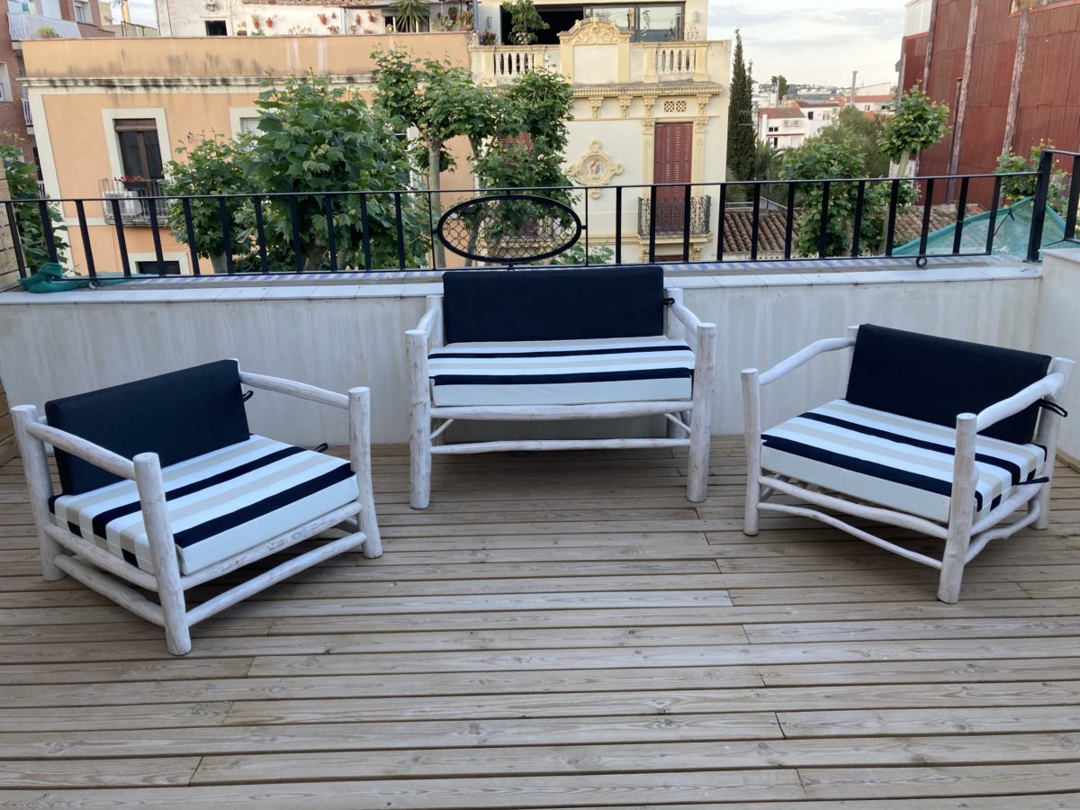 Butaques d'exterior amb coixins de ratlles en una terrassa de fusta