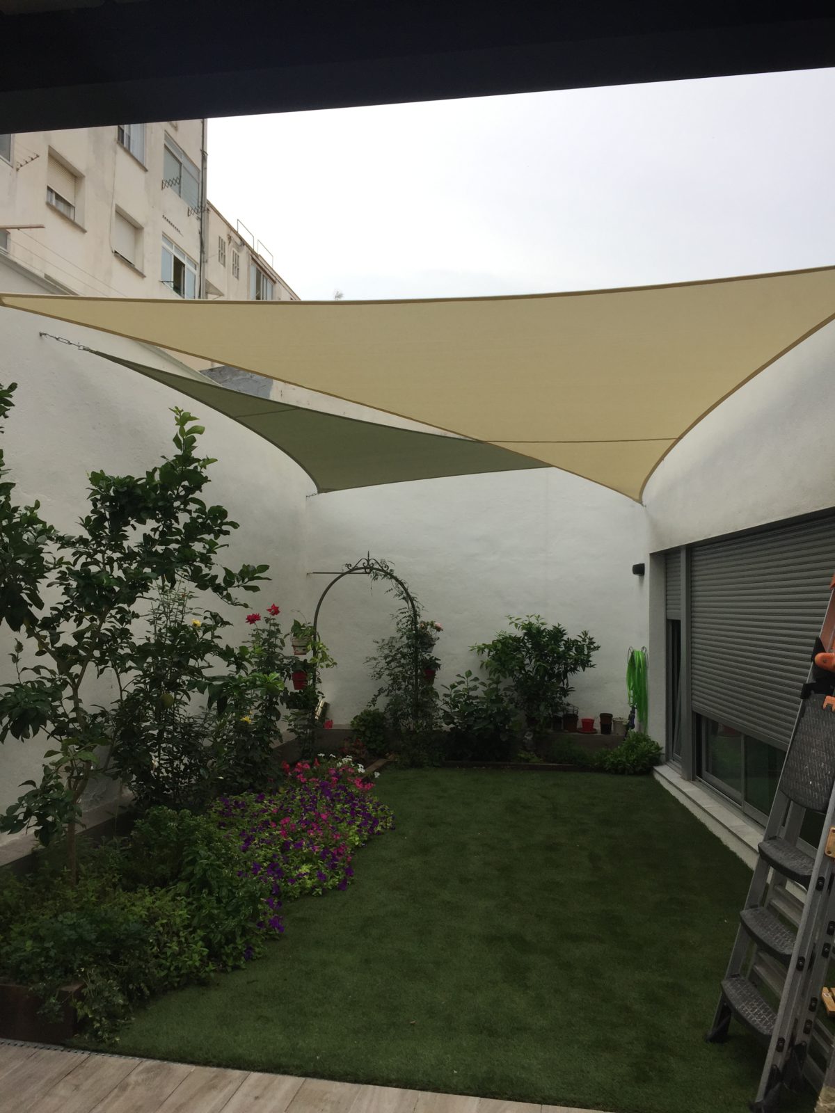 Veles d'ombra beix sobre la gespa d'un jardí